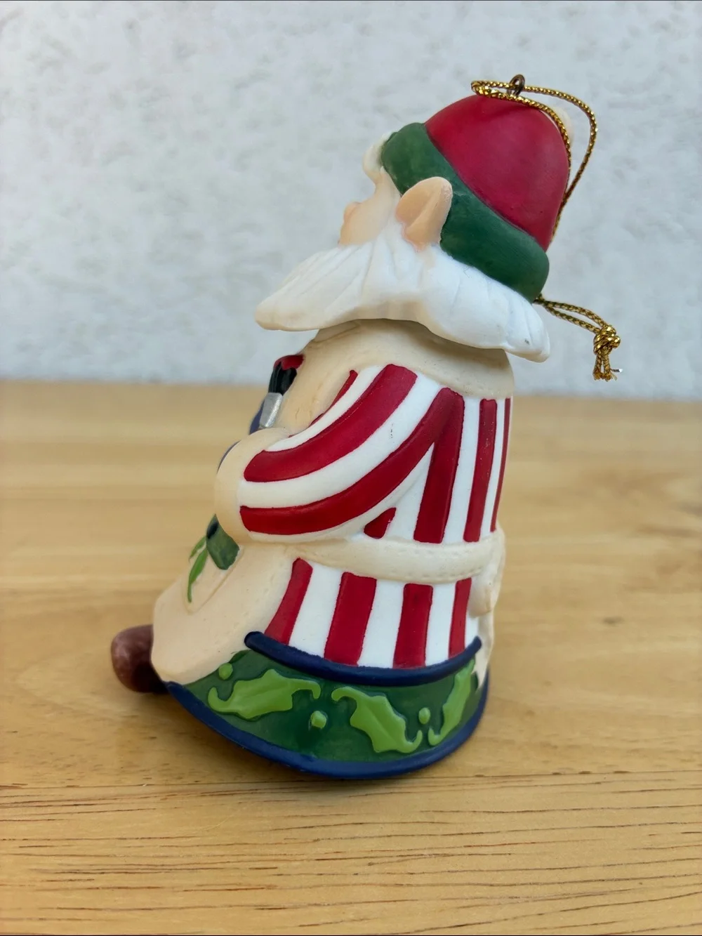Ceramic elf painting a bird house bell ornament with little floppy legs